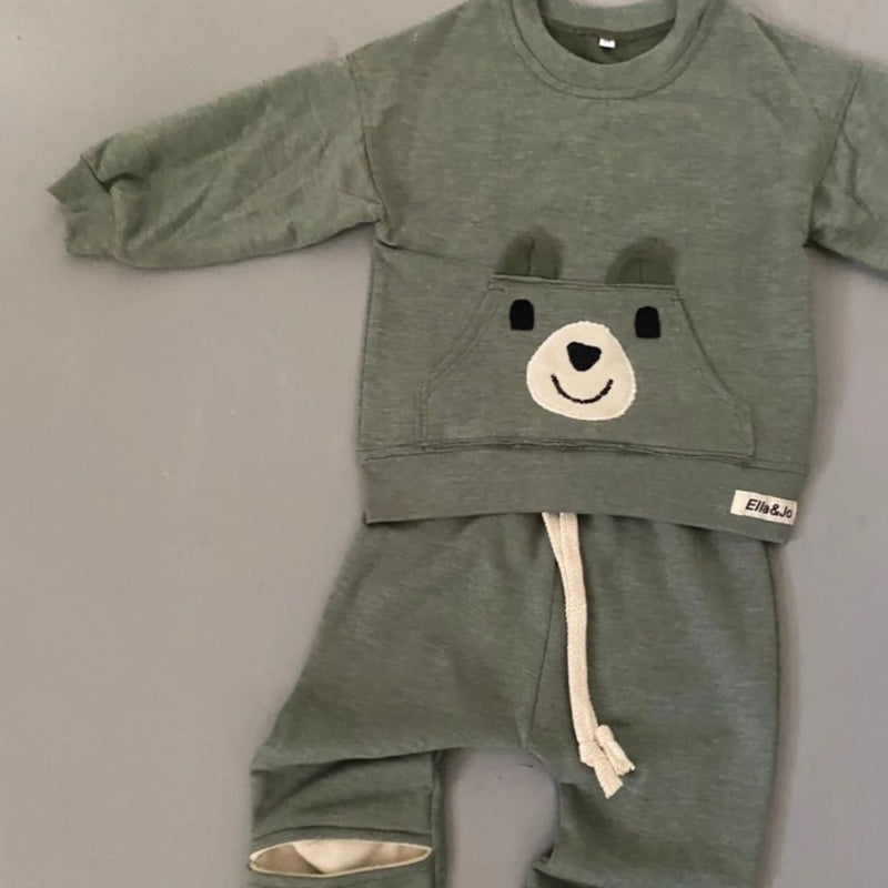 The Khaki Bear Tracksuit is not just an ordinary one. It has been designed with comfort, style and play time in mind. Front pocket has bear face detail, and the legs has soft cushion openings which provides extra cushioning when little one is crawling or sitting.

Colour - Khaki Melange