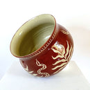 A sgraffito craved pot planter with snake and palm leaf motif.