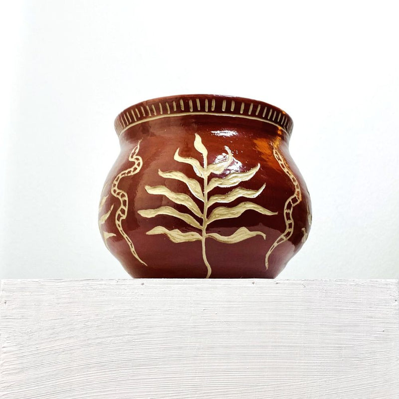 A sgraffito craved pot planter with snake and palm leaf motif.
