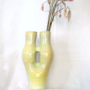 A Tall coil build stoneware vase extending into two necks covered with a melon green glaze.