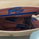 Lighter, softer and with an easy pop up handle and a detachable crossbody strap.  Meet the all new Brunch Bag.  Fully lined with custom lining, printed in South Africa. 100% Soft light grey leather with a silver/white sequins finish. Dimensions 23 cm (width) x 18 cm (height) 11cm (bottom) x 6cm (top)