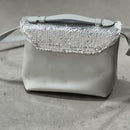 Lighter, softer and with an easy pop up handle and a detachable crossbody strap.  Meet the all new Brunch Bag.  Fully lined with custom lining, printed in South Africa. 100% Soft light grey leather with a silver/white sequins finish. Dimensions 23 cm (width) x 18 cm (height) 11cm (bottom) x 6cm (top)
