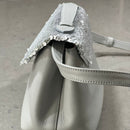 Lighter, softer and with an easy pop up handle and a detachable crossbody strap.  Meet the all new Brunch Bag.  Fully lined with custom lining, printed in South Africa. 100% Soft light grey leather with a silver/white sequins finish. Dimensions 23 cm (width) x 18 cm (height) 11cm (bottom) x 6cm (top)